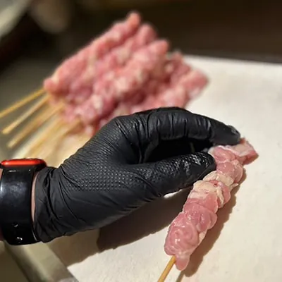 鶏肉を一本ずつ手打ちで串に刺すところ